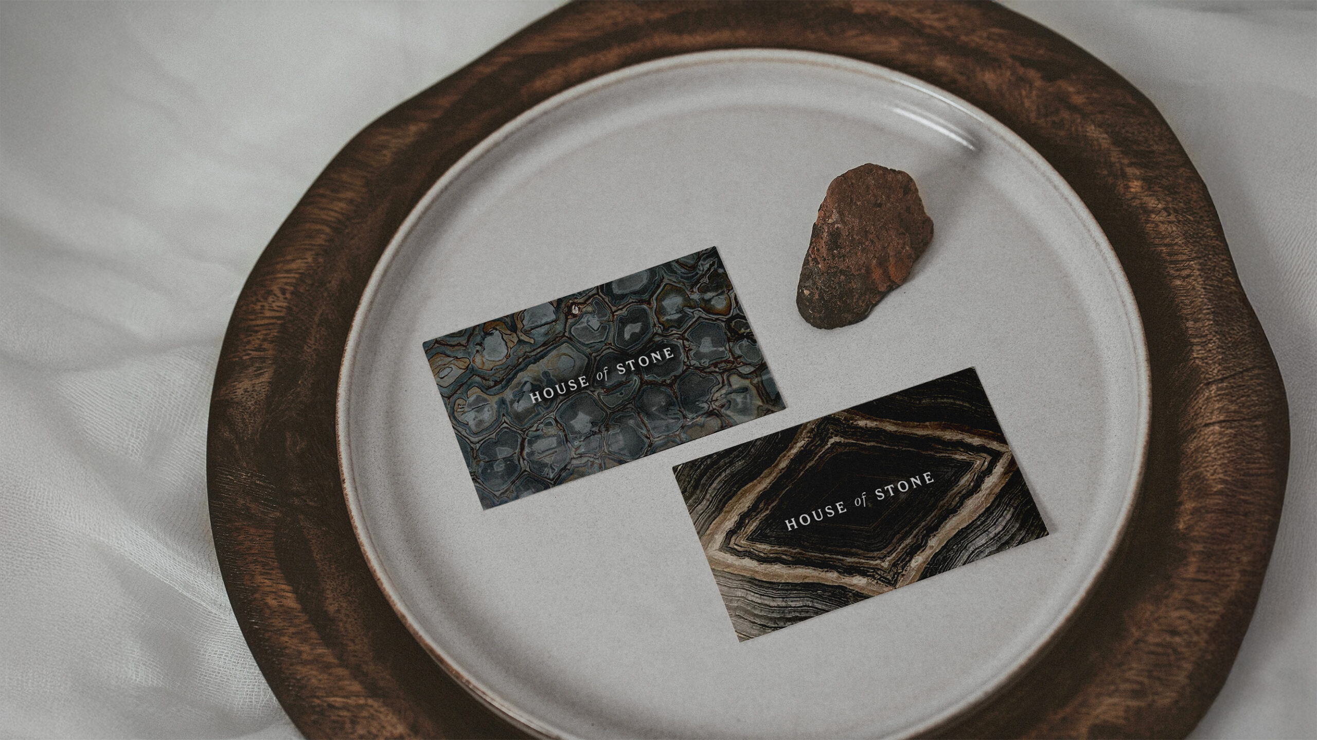 Visitekaartjes van House of Stone op een bord met een klein steentje, op een houten dienblad