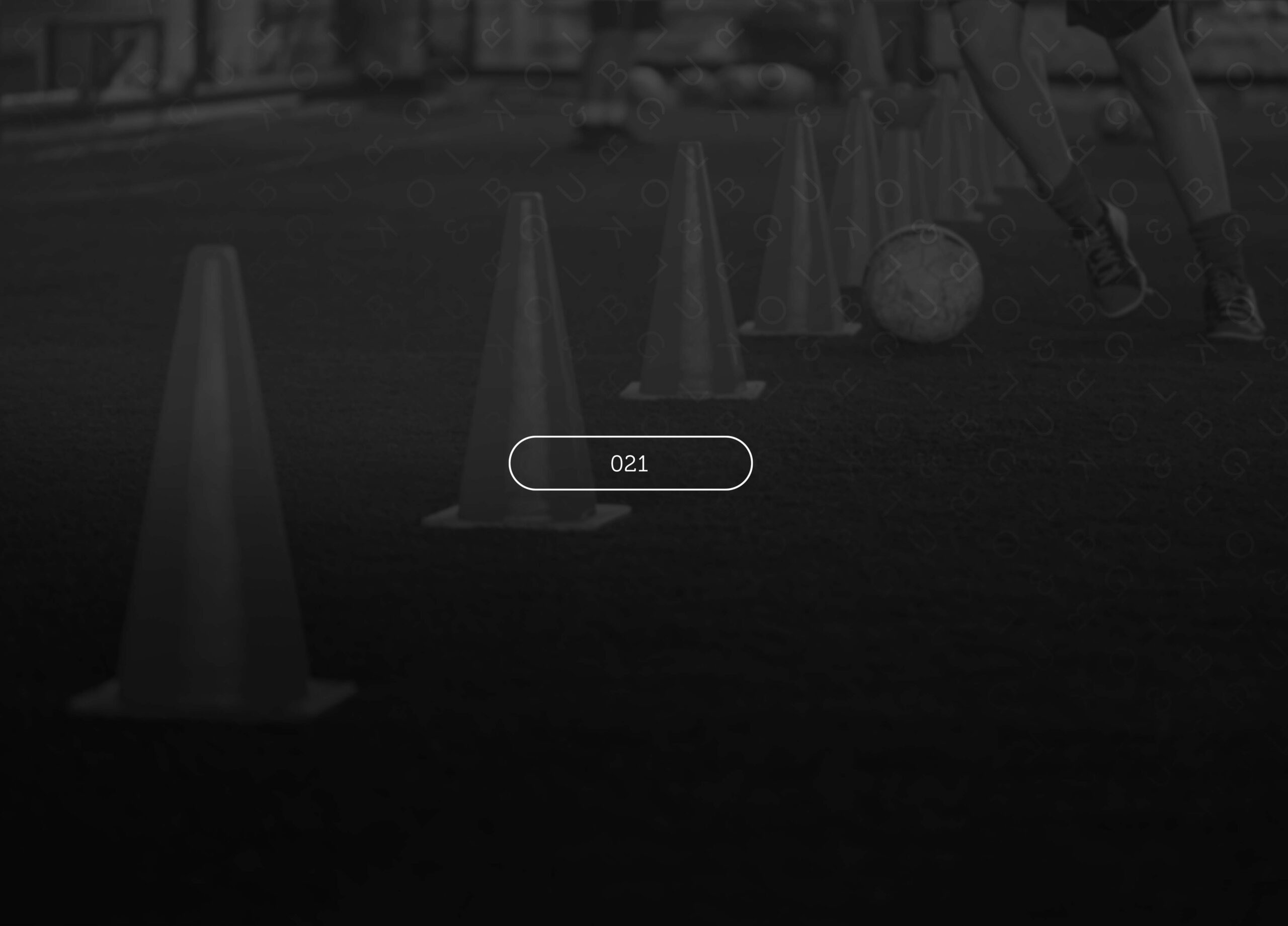 Football training cones on a pitch with a blurred player and ball behind them