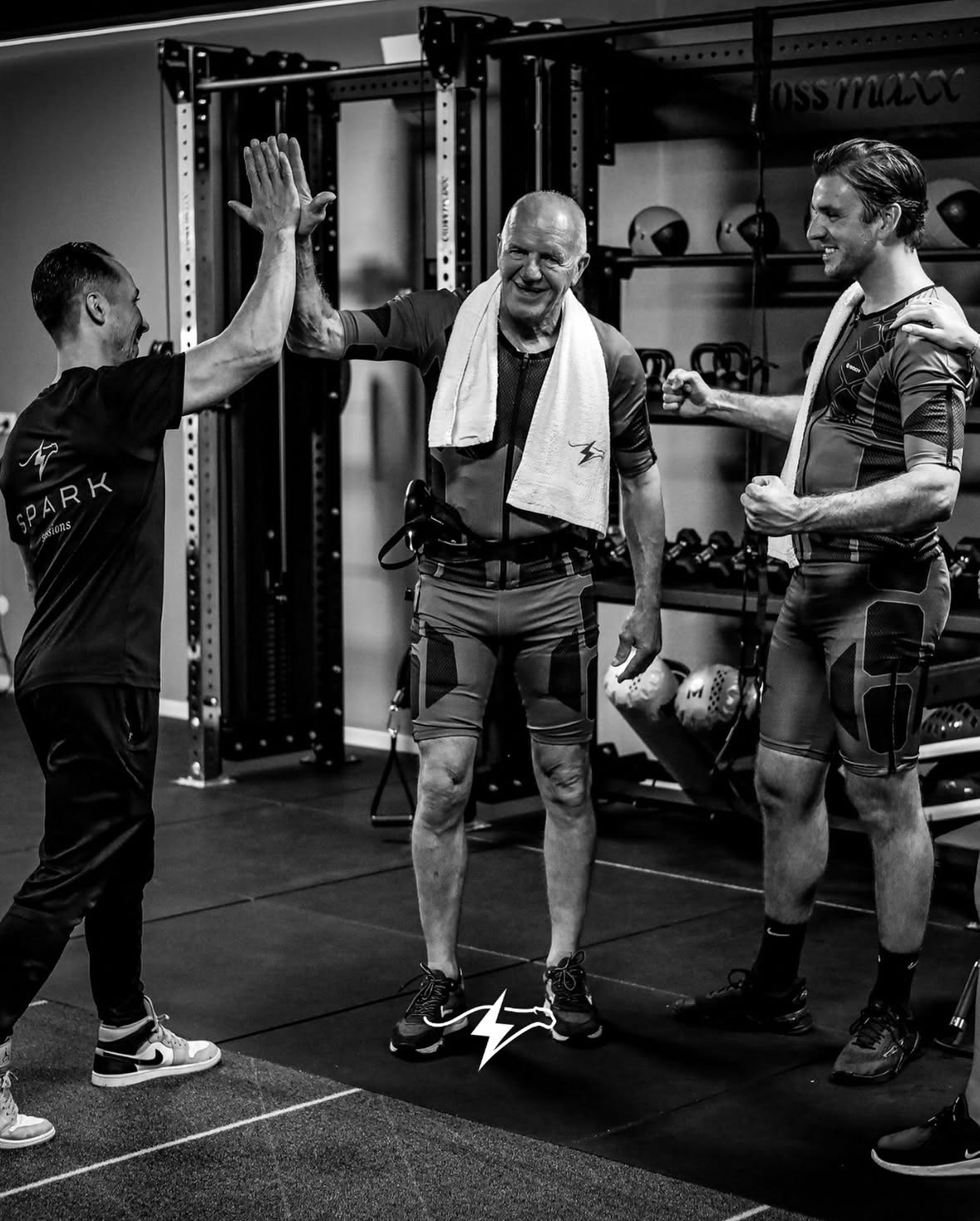 Drie mannen geven elkaar een high five in een sportschool