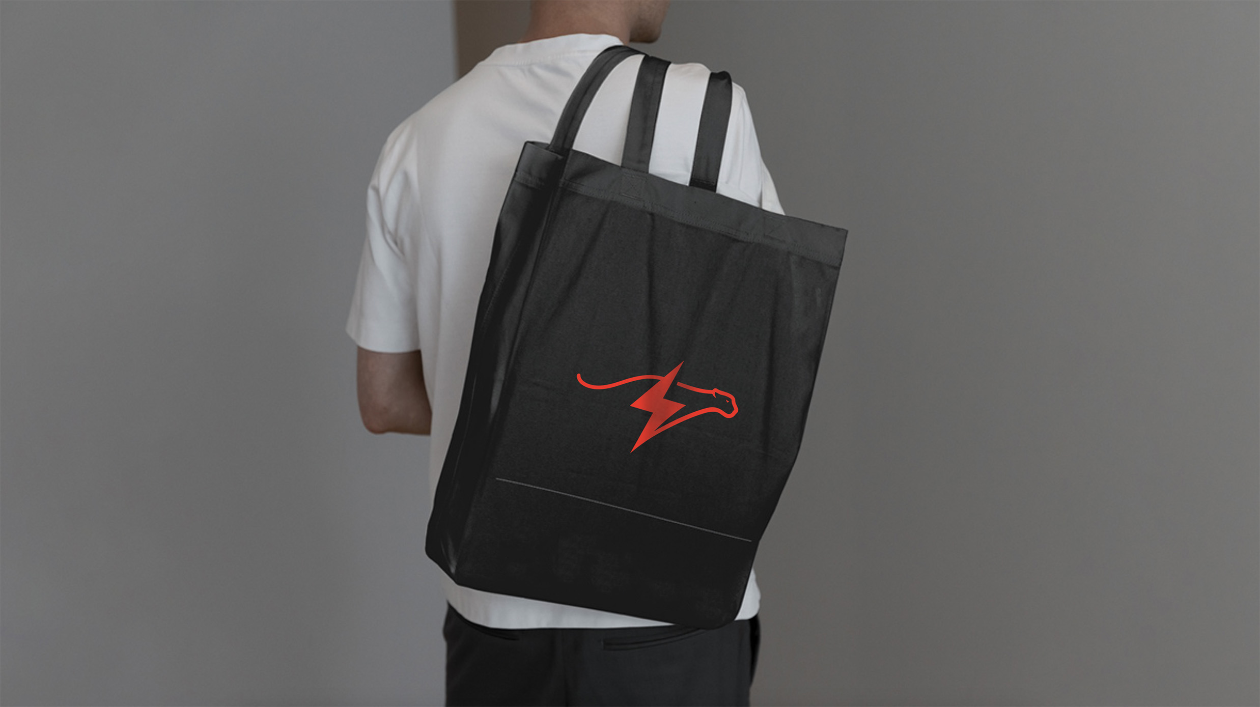 Man draagt een zwarte tas met rood logo over zijn schouder