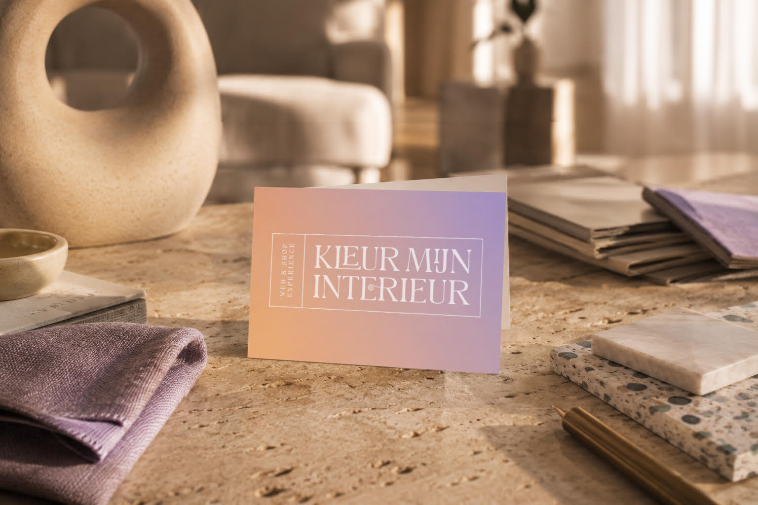 Visitekaartje van Kleur Mijn Interieur op een tafel met paarse stofmonsters en een vaas